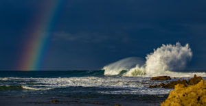 crashing waves with rainbow above