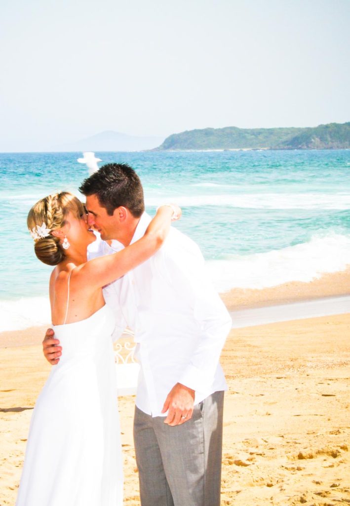 bride and grooms first kiss on the beach